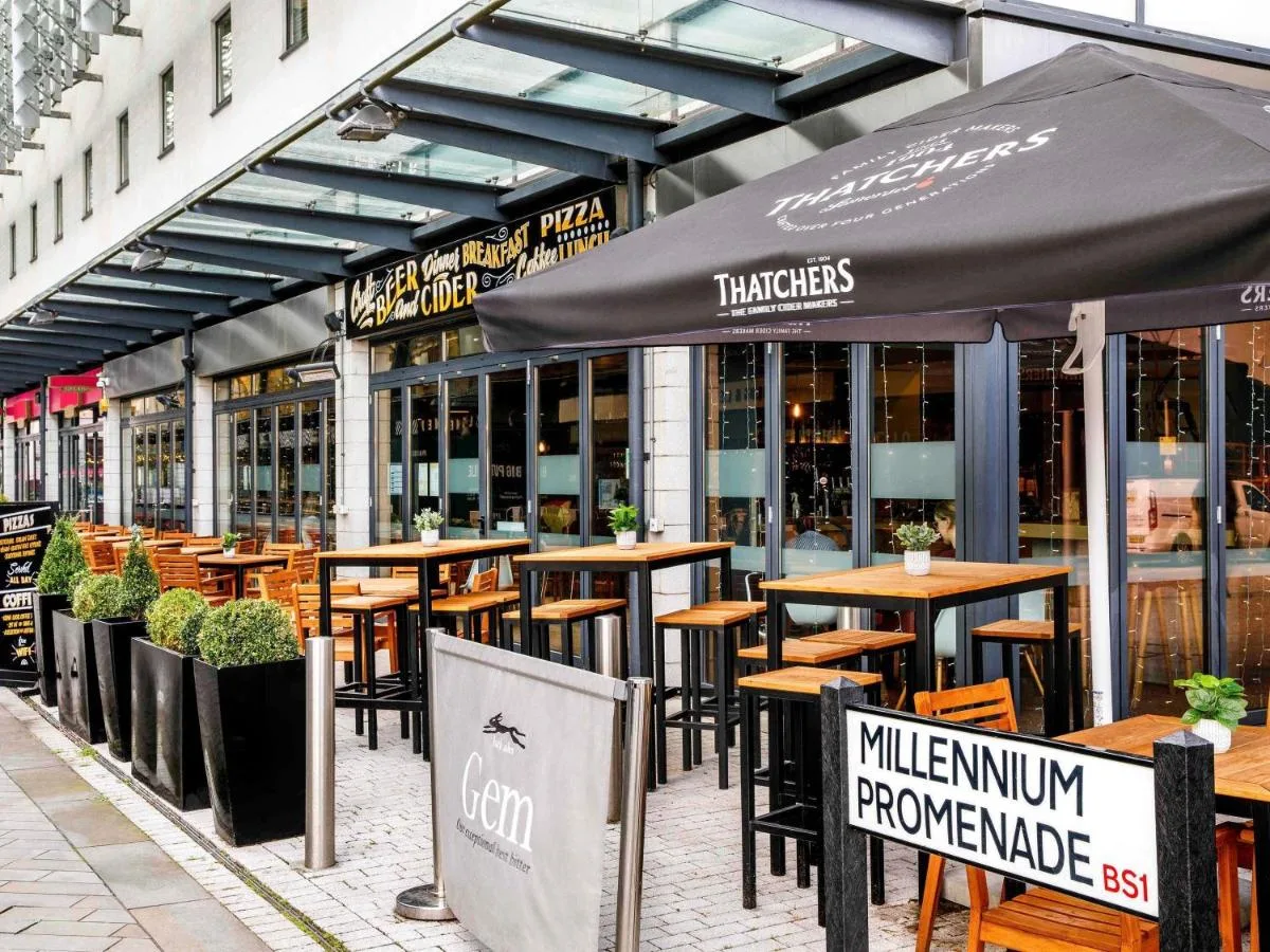 a restaurant with tables and umbrellas on a street at ibis Bristol Centre in Bristol