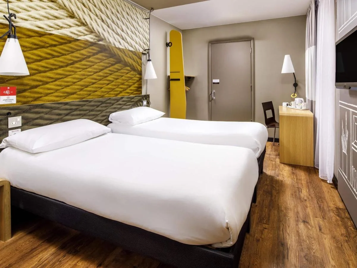 a hotel room with two beds and a yellow wall at ibis Bristol Centre in Bristol