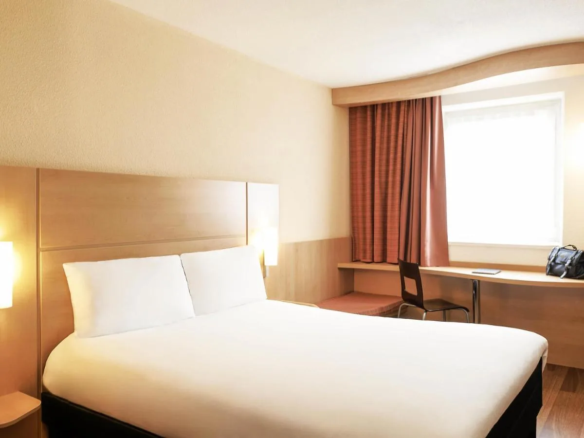 a hotel room with a bed and a desk and a window at ibis Bristol Centre in Bristol