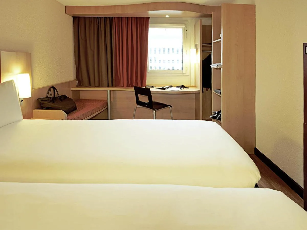 a hotel room with a white bed and a chair at ibis Bristol Centre in Bristol